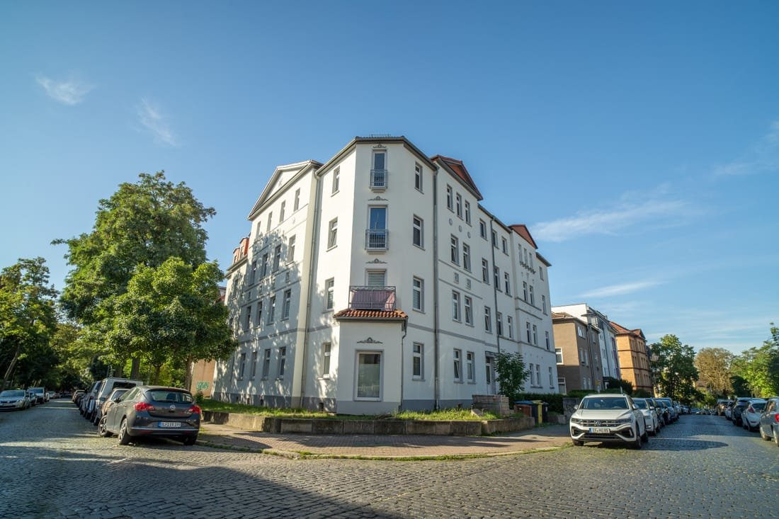 Weiß saniertes Eckhaus mit Erker an einer Straßenkreuzung