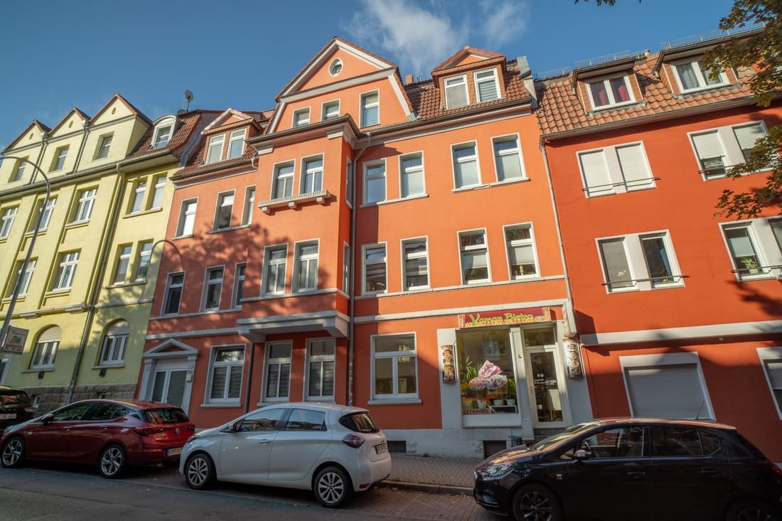 Rot gestrichenes Mehrfamilienhaus mit Ladengeschäft im Erdgeschoss
